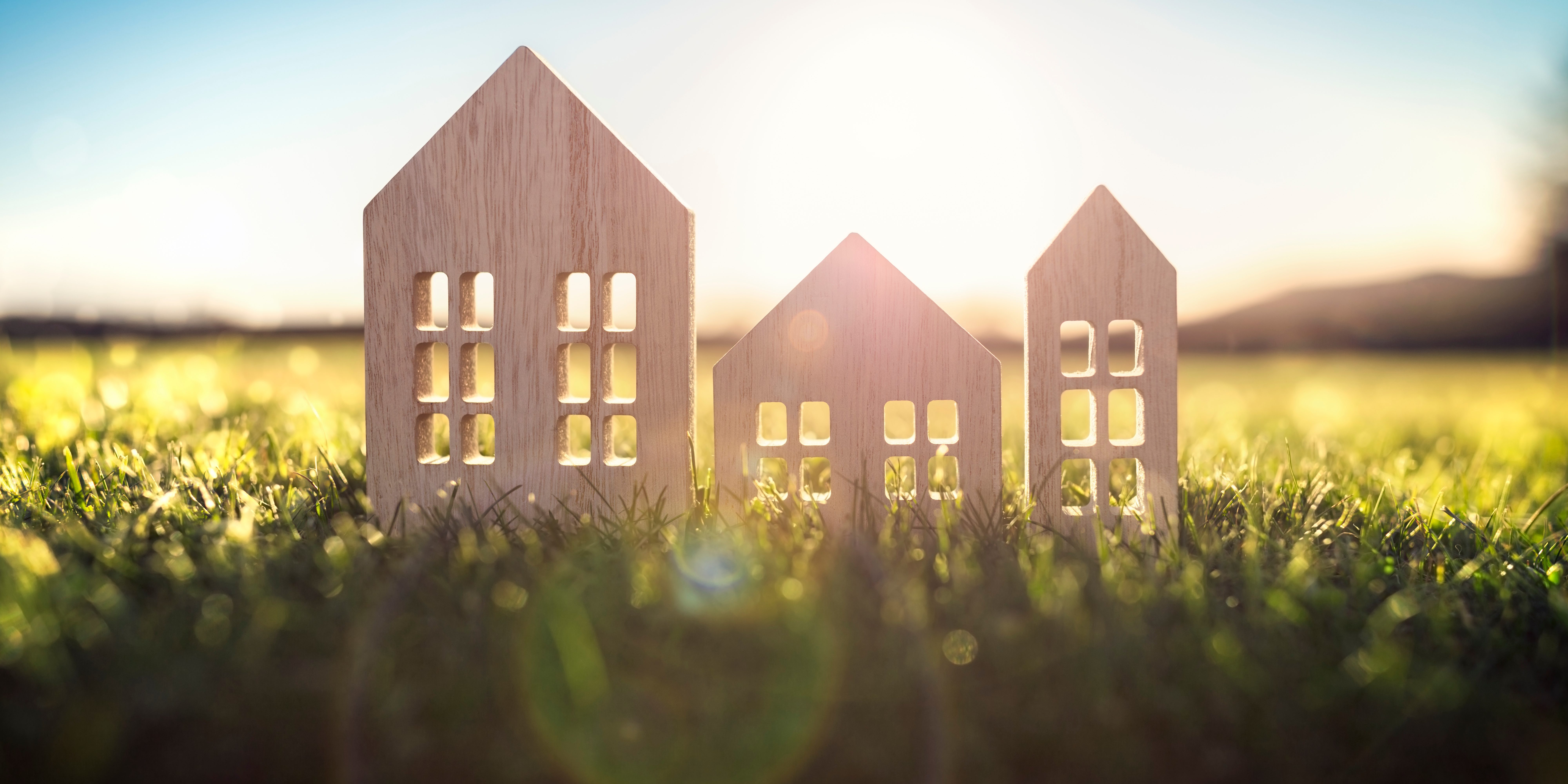 Ecological wood  model house in empty field at sunset