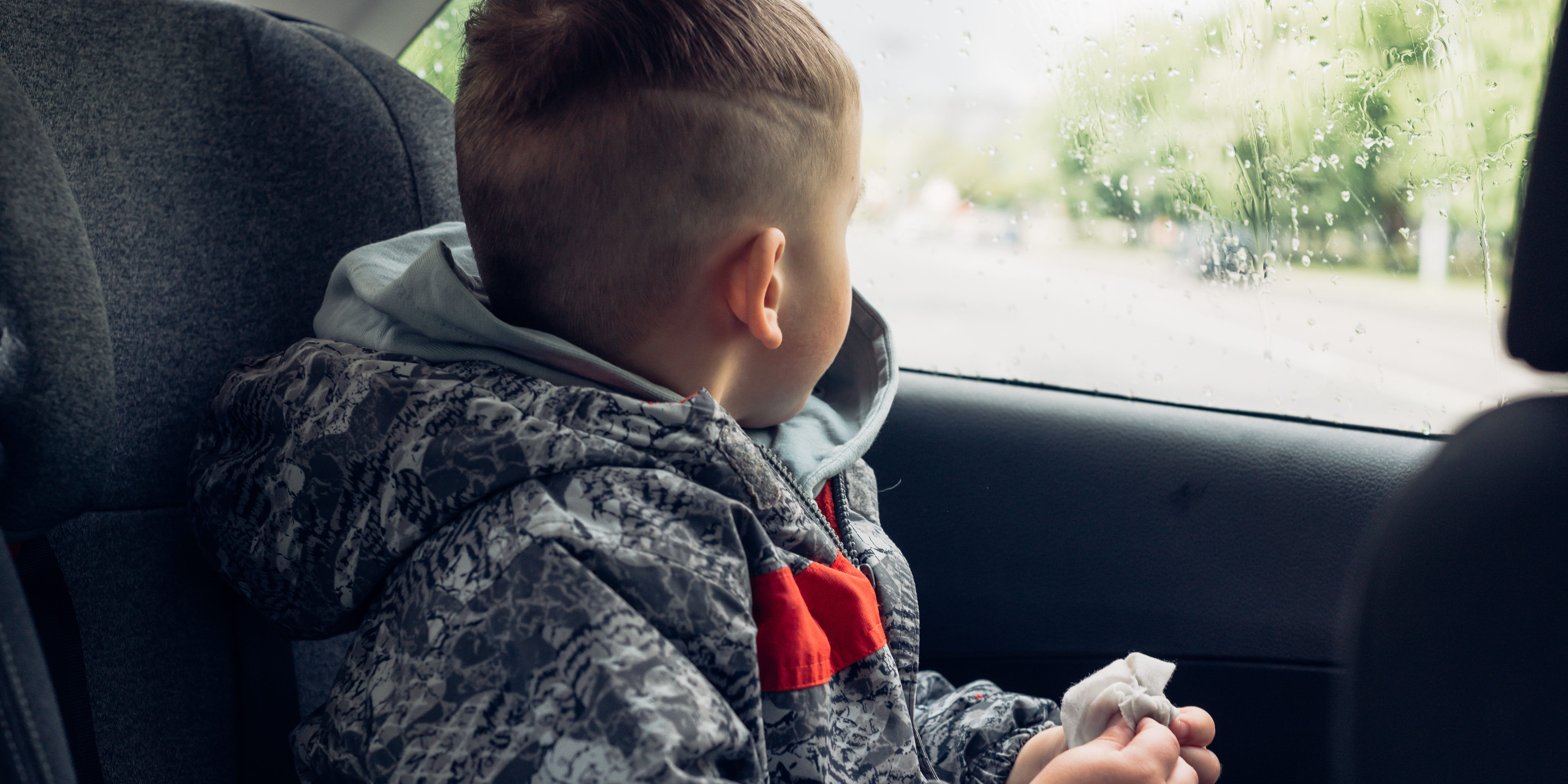 Little boy sitting in the back of a car and staring out of the window