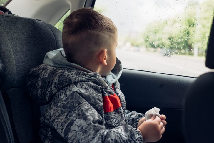 Little boy sitting in the back of a car and staring out of the window